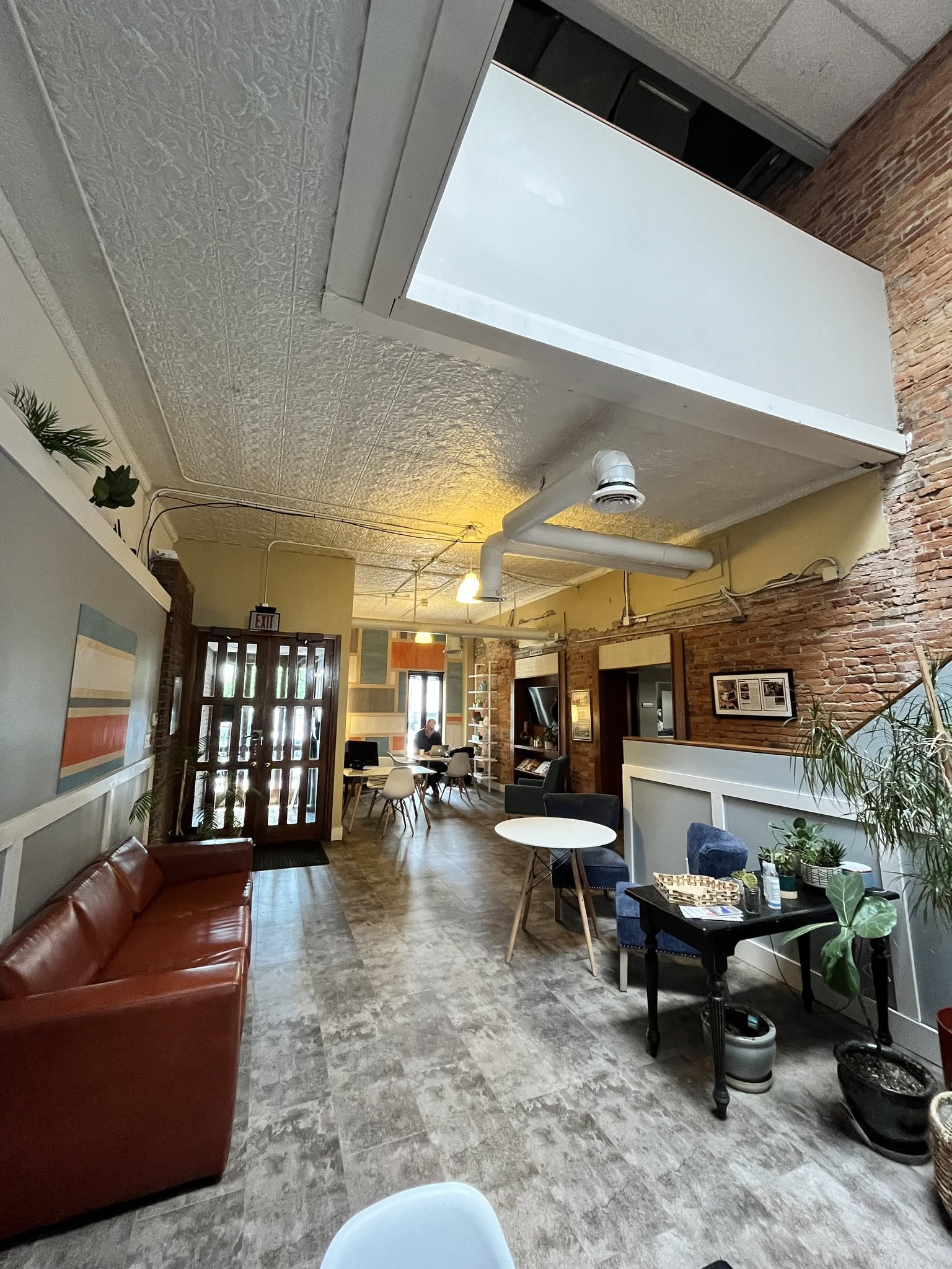 Ground floor lobby with exposed brick, tin ceilings, and leather seating